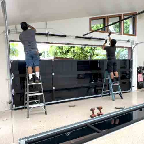 Technician installing a contemporary full-view glass garage door