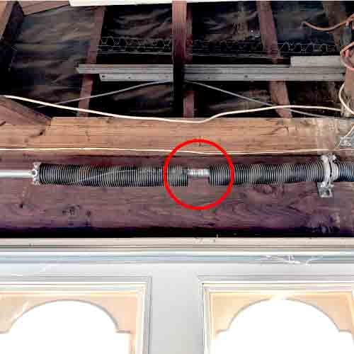 a broken torsion spring discovered during a garage door safety and maintenance inspection