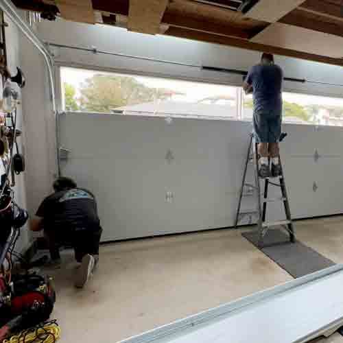 Champion technicians performing spring tension adjustment and track alignment during a routine maintenance visit in Orange County