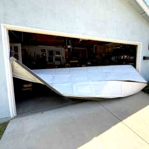 A garage door that has visibly buckled and crashed off the tracks, highlighting the need for immediate emergency off-track repair service