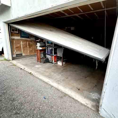 garage door dislodged from the tracks due to worn and broken rollers highlighting the safety risk