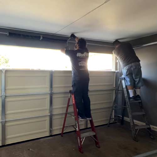 Garage door technician adjusting door hardware during a residential repair in Santa Ana