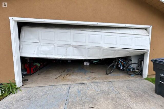 Damaged garage door stuck partly open before emergency repair