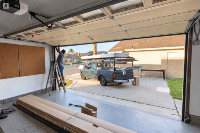 Technician working near the cable drum and upper track of a garage door.