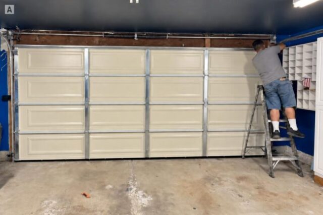 Technician adjusting garage door hardware along the side of a sectional door.