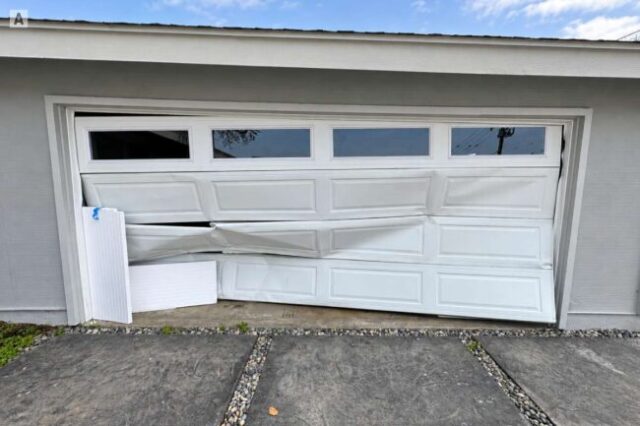 Garage door with severe impact damage leaving the garage opening unsecured