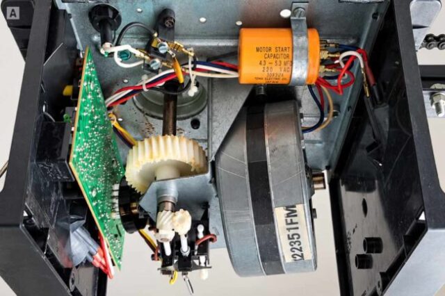 Garage Door Opener Gear Repair Inside a garage door opener showing the motor, capacitor, circuit board, and drive gears
