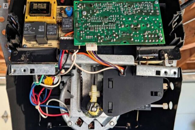Garage Door Opener Logic Board Repair Garage door opener with the cover removed showing the installed logic board and wiring