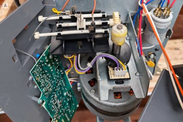 Garage Door Opener Module Repair Open garage door opener showing the internal module, gears, wiring, and capacitor