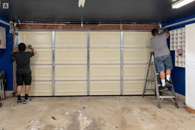 Technicians working on the top section of a garage door.