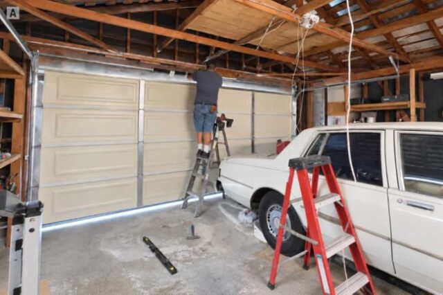 Technician working on the torsion system above a residential garage door.