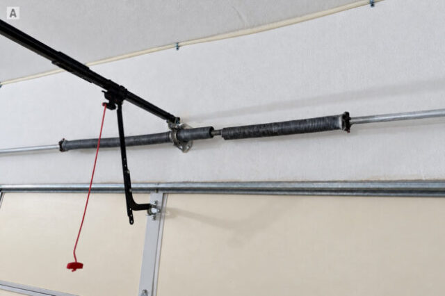 Broken torsion spring above a closed garage door during an emergency repair call