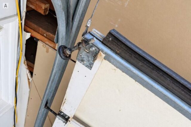 Off-Track Garage Door Roller and Cable Close-up of garage door roller, cable, and track on an off-track door