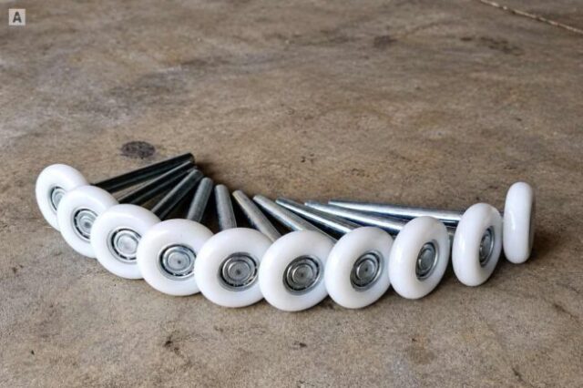 Set of white ball-bearing garage door rollers on a concrete floor