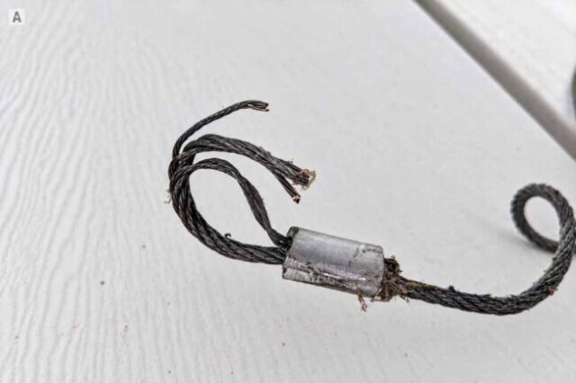 Close-up of a broken garage door cable loop with frayed steel strands.