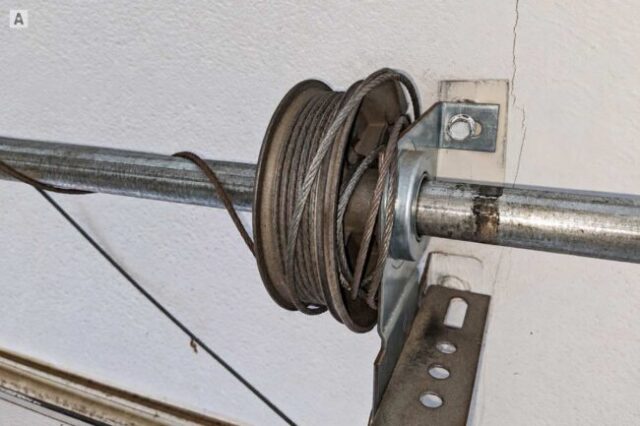 Garage door cable loose and wrapped unevenly around the cable drum after losing tension.