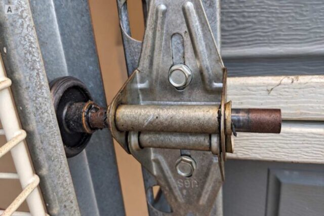 Close-up of a garage door roller bearing and stem at the hinge and track